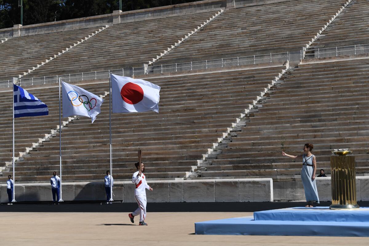 At a scaled-down ceremony at Panathenaic Stadium in Athens on Thursday, only a few people were permitted to watch Greek officials hand the traditional flame to the Tokyo 2020 organizing committee.
