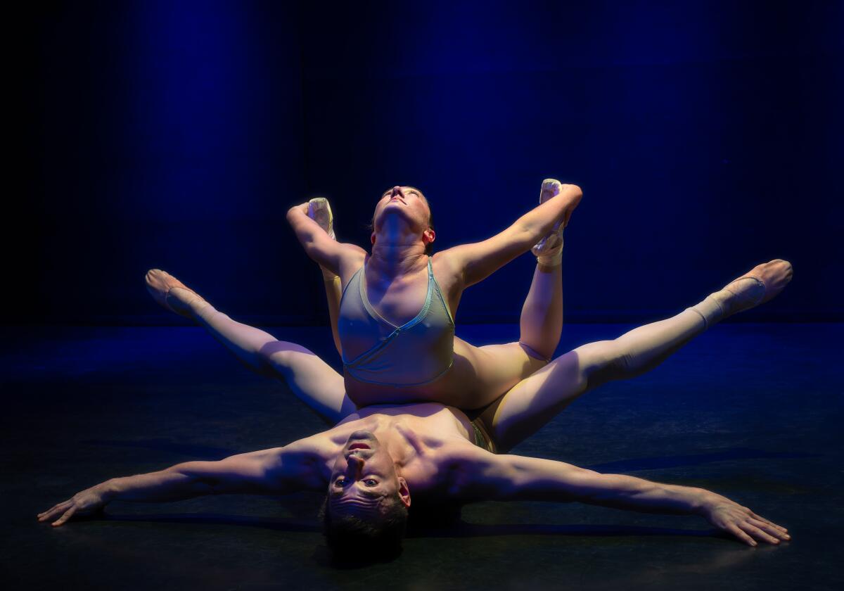 Two dancers stretch onstage.