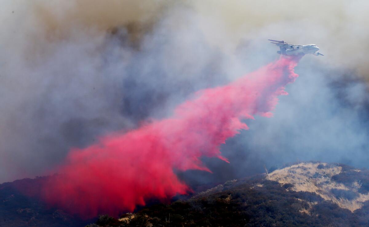 A firefighting airplane drops fire retardant on the foothills of the San Bernardino National Forest above Lytle Creek.