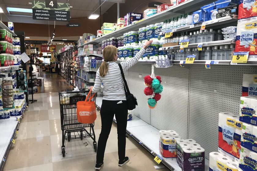 CALABASAS, CA - NOVEMBER 19, 2020: A shopper reaches for a roll of toilet paper located above a partially empty shelf at Ralph's market in Calabasas. (Mel Melcon / Los Angeles Times)