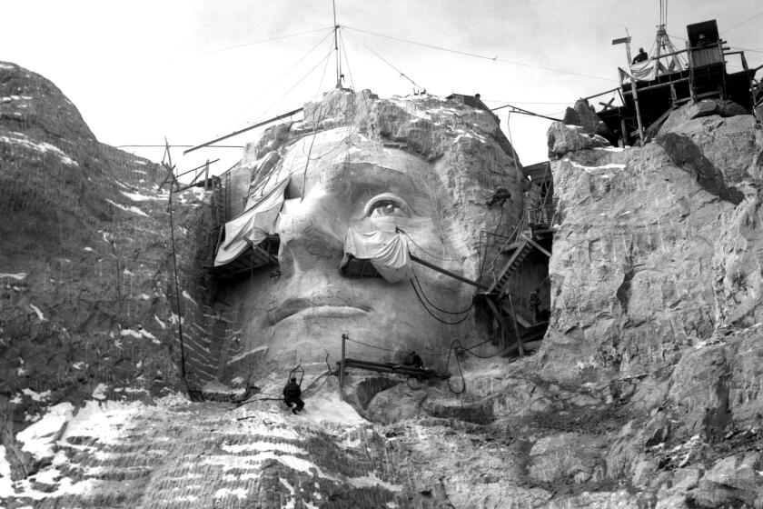 Stone carvers on scaffolding and hoists carve the face of Thomas Jefferson into Mount Rushmore. (Photo by George Rinhart/Corbis via Getty Images)