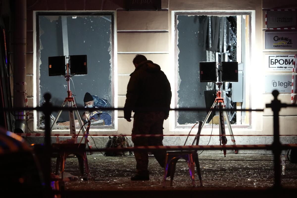 Silhouette of a man outside a building with blown out windows and exterior floodlights facing it.