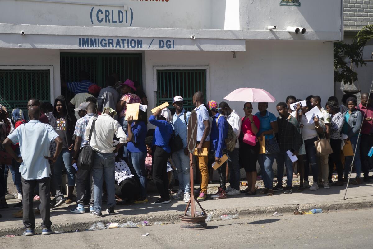 Un grupo de haitianos hacen una fila frente a una oficina de inmigración mientras esperan su turno