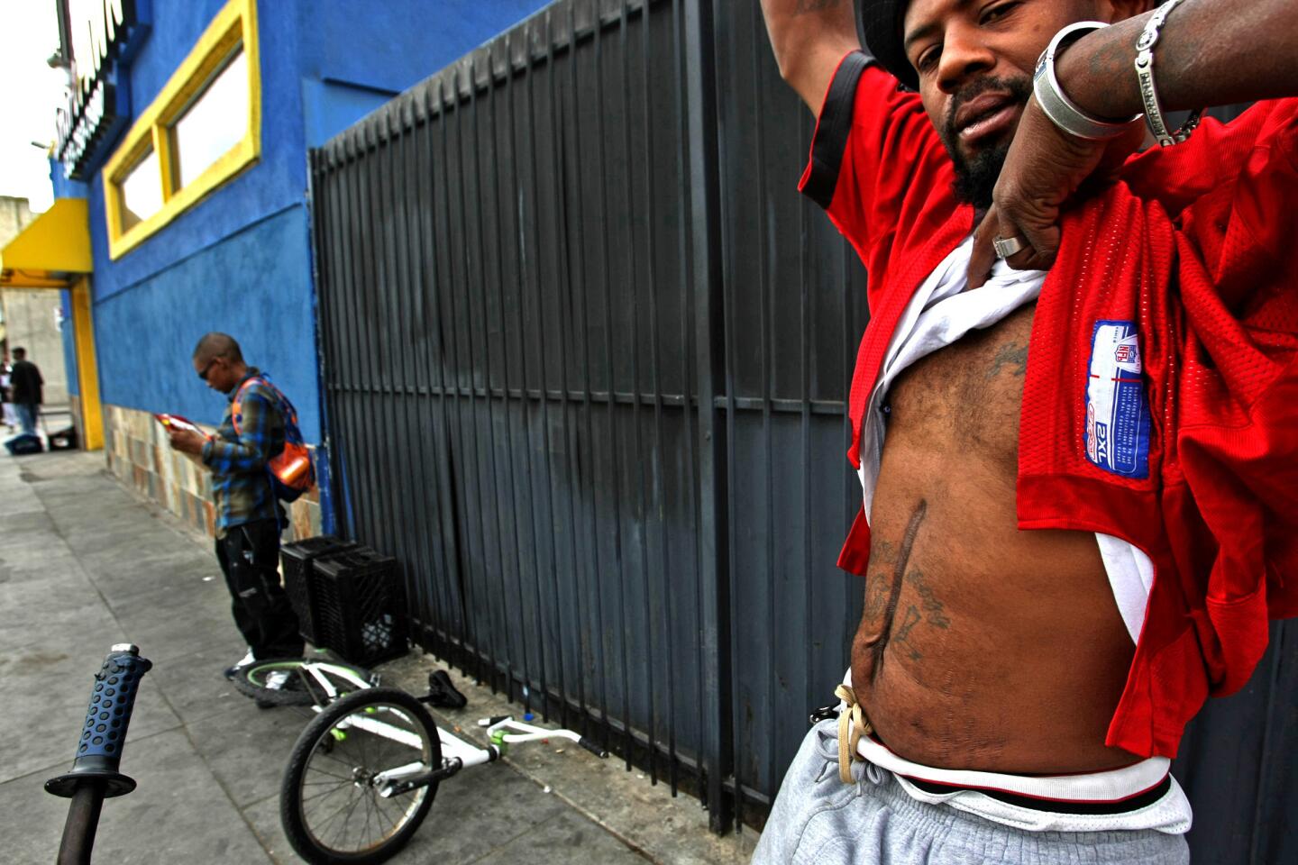 L. Christopher Caver Jr., 38, shows a scar on his stomach, a result of a 2012 shooting when he was hit seven times inside his car. He has lived in the Westmont area of South L.A. for more than a decade.