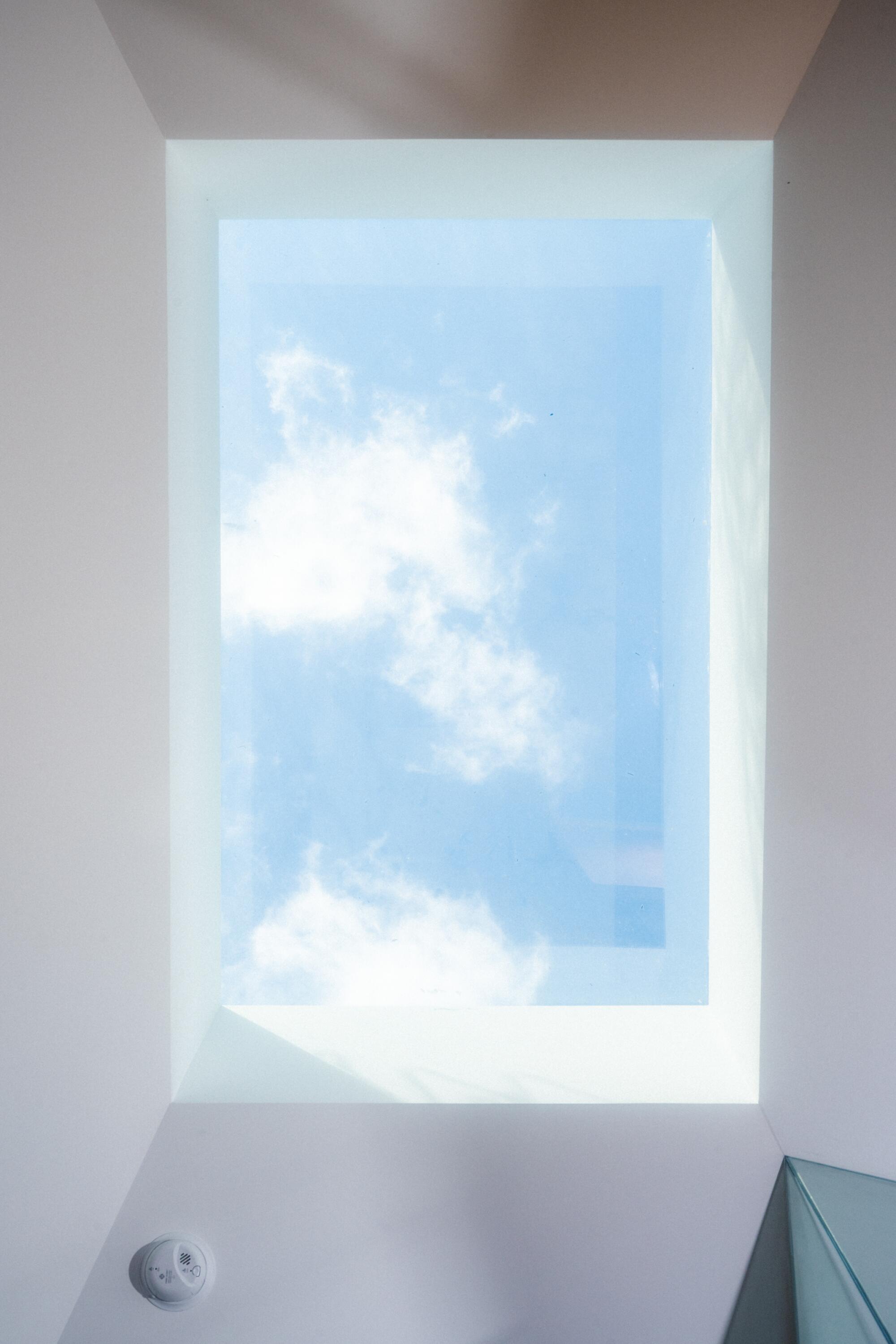 The image of a skylight showing a blue sky and a few clouds.