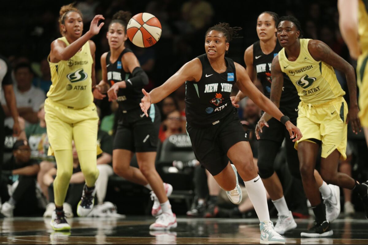 FILE - In this Aug. 11, 2019, file photo, New York Liberty guard Tanisha Wright, center, goes after a loose ball during the first half of the team's WNBA basketball game against the Seattle Storm at Barclays Center in New York. The Atlanta Dream hired longtime WNBA player Tanisha Wright as its new head coach on Tuesday, Oct. 12, 2021, looking to bring stability to a team that struggled under two interim coaches this past season. The 37-year-old Wright played 14 seasons with the Seattle Storm, New York Liberty and Minnesota Lynx. (AP Photo/Kathy Willens, File)