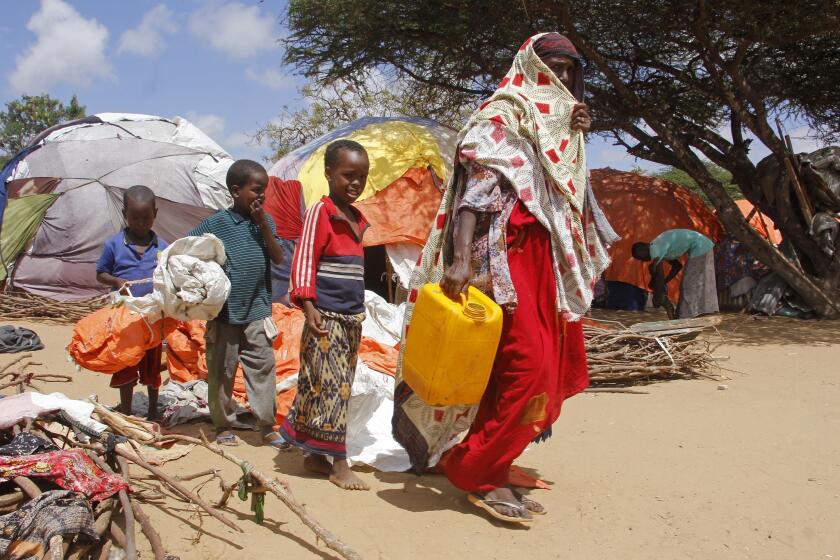 Una mujer camina con sus hijos en un campamento para desplazados después de que huyeran de una sequía, el martes 26 de septiembre de 2023, en las afueras de Mogadiscio, Somalia. (AP Foto/Farah Abdi Warsameh)