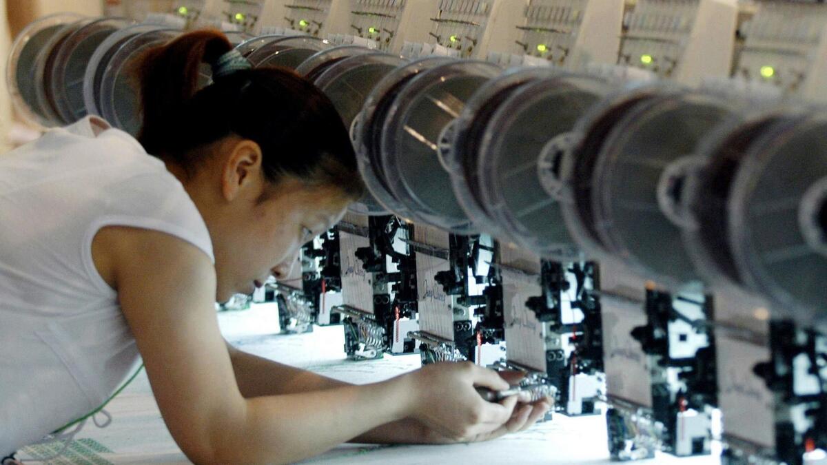 A worker adjusts an embroidery machine at a garment fair in New Delhi.