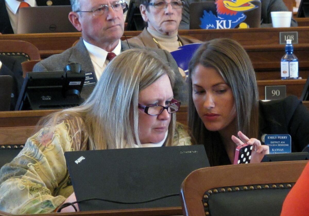 Kansas state Reps. Julie Menghini, left, and Emily Perry confer during a House debate on a bill dealing with gay marriage.