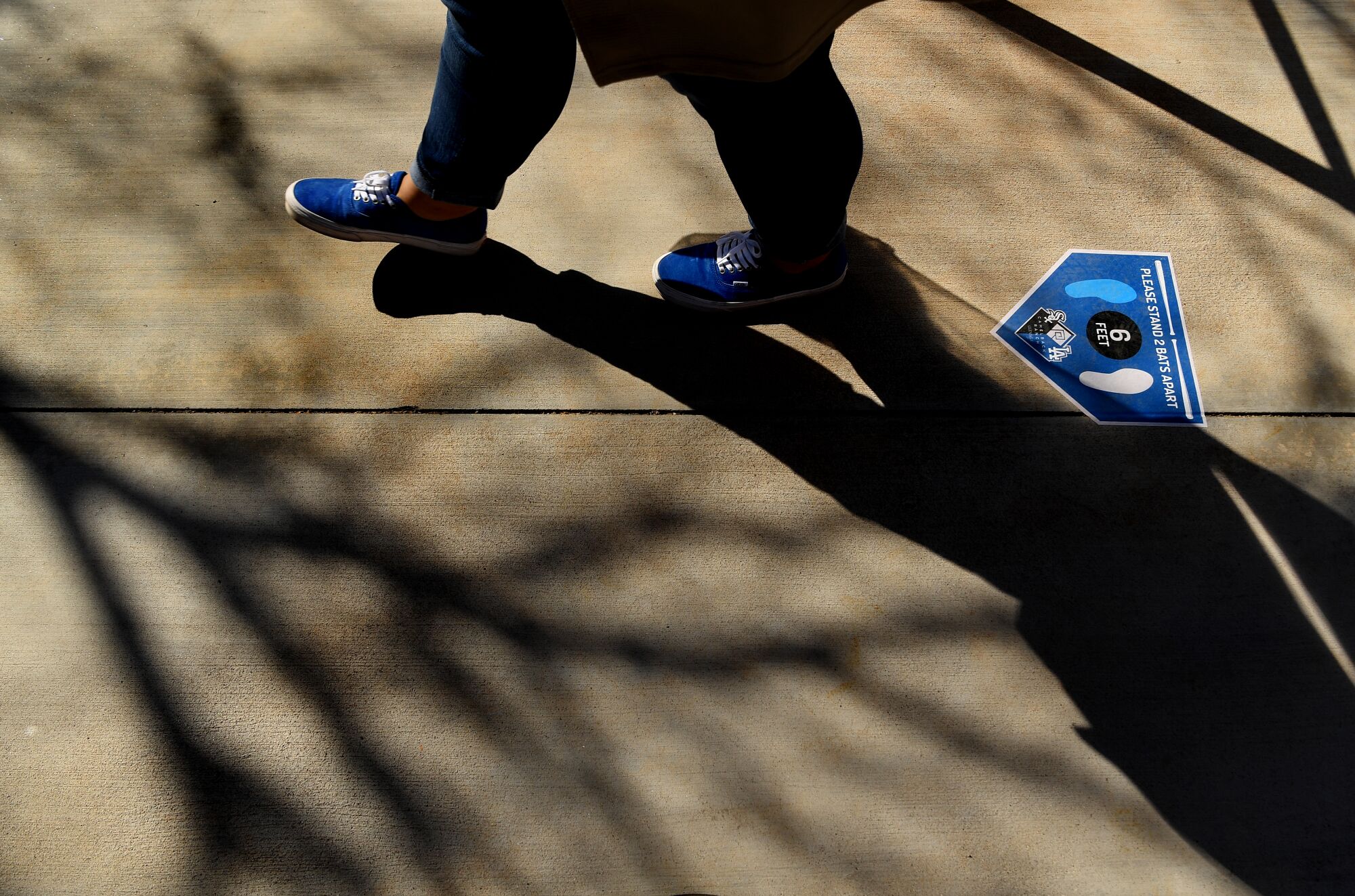A fan walks past a "keep your distance" sign during a game