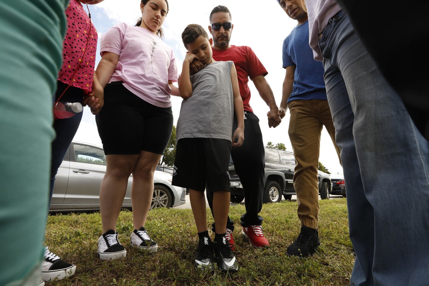 Brandon Sanchez, 9, prays with his father Victor Sanchez, center, of Coral Springs, Fla., along with other family members and friends in front of Marjorie Stoneman Douglas High School on Sunday, Feb. 18, 2018.