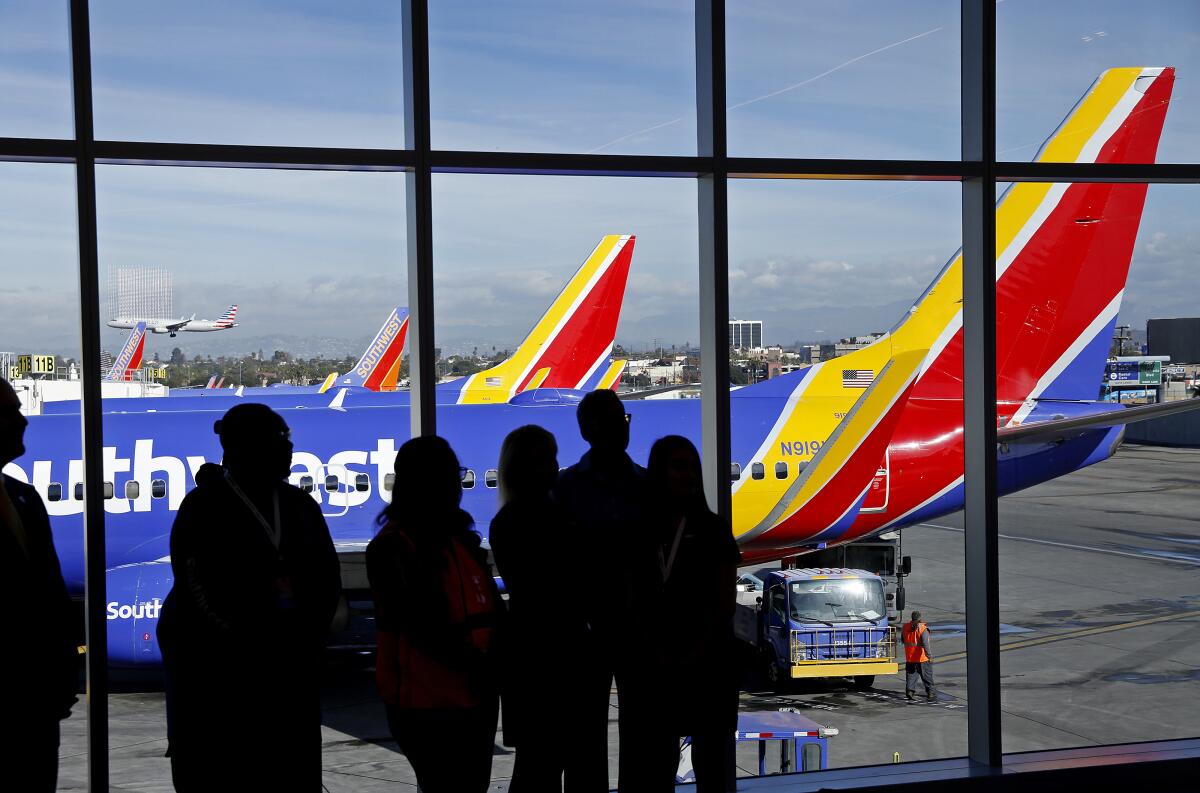 People look out an airport terminal window at Southwest Airlines aircraft.