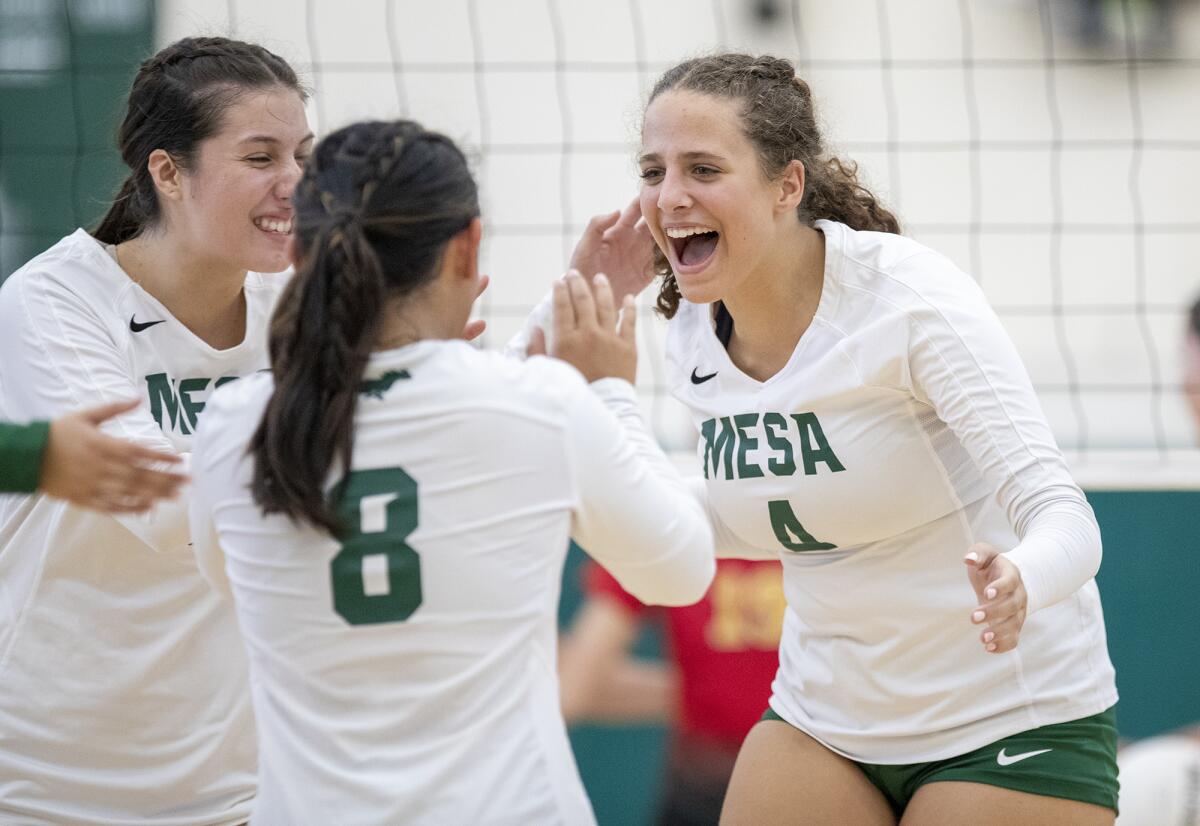 Costa Mesa's Natasha Ruiz, left, Rosalynn Madriaga, center, and Sophia Winters celebrate a point Tuesday.