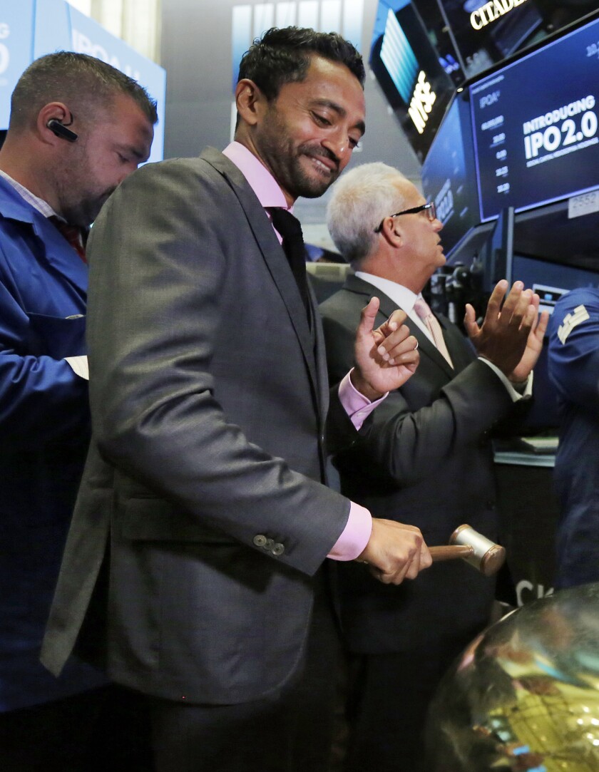 FILE - Social Capital Hedosophia Holdings Corp. CEO, Founder and Chairman Chamath Palihapitiya, center, rings a ceremonial bell on the floor of the New York Stock Exchange, Thursday, Sept. 14, 2017. Palihapitiya, a Golden State Warriors NBA basketball team minority owner who said "nobody cares" about the Uyghurs in China, is under fire and the team is distancing itself from him. On the latest edition of his All-In Podcast, the billionaire dismissed the situation in China, which is accused by the U.S. of genocide and crimes against humanity with treatment of the Uyghurs Muslim minority population in its Xinjiang region of Northwest China. (AP Photo/Richard Drew, File)