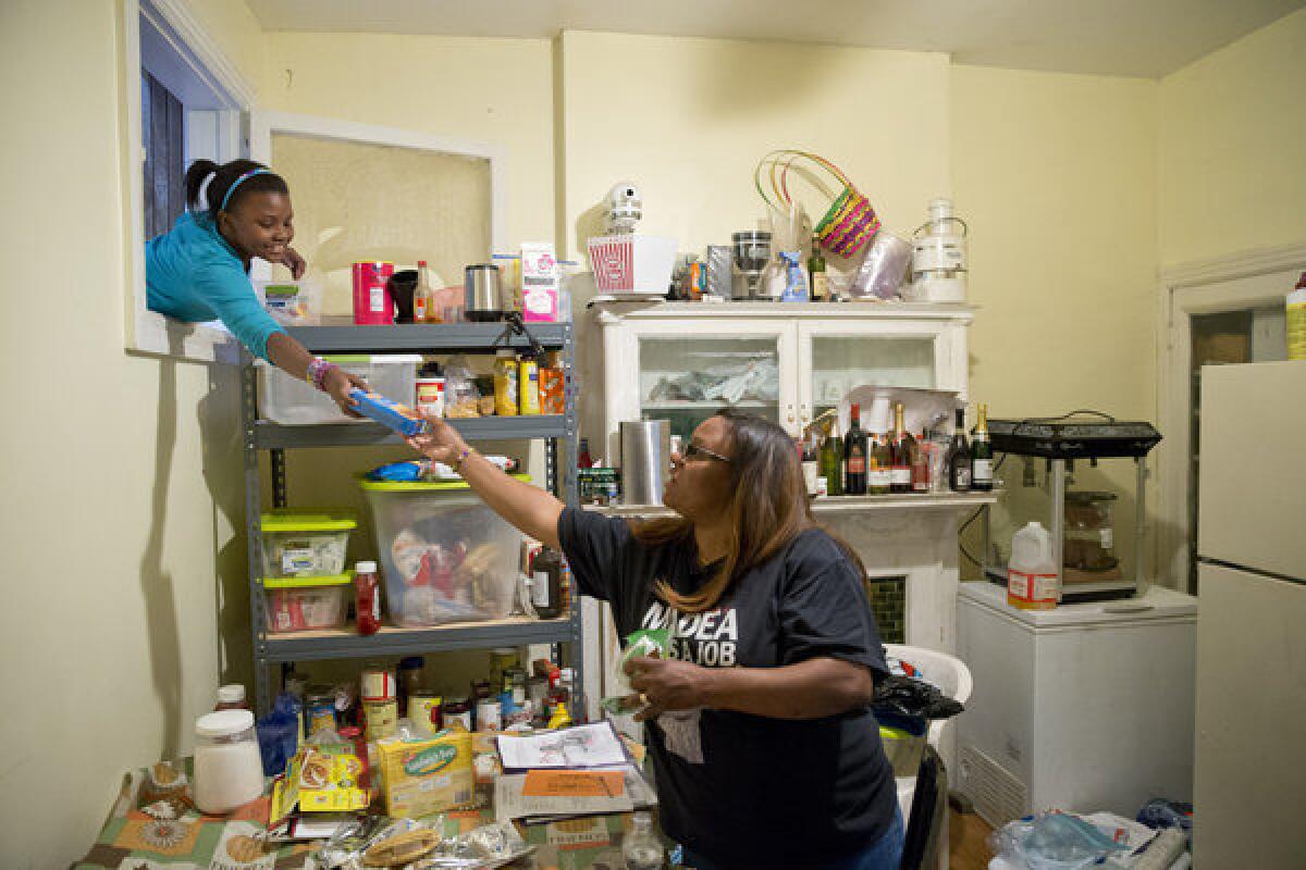 Jennifer Donald, whose family receives money from the Supplemental Nutrition Assistance Program also known as food stamps, takes a box of taco seasoning from her daughter Jayla, 10, in Philadelphia. Families already buffeted by difficult economic times saw their food stamps benefits drop Friday.