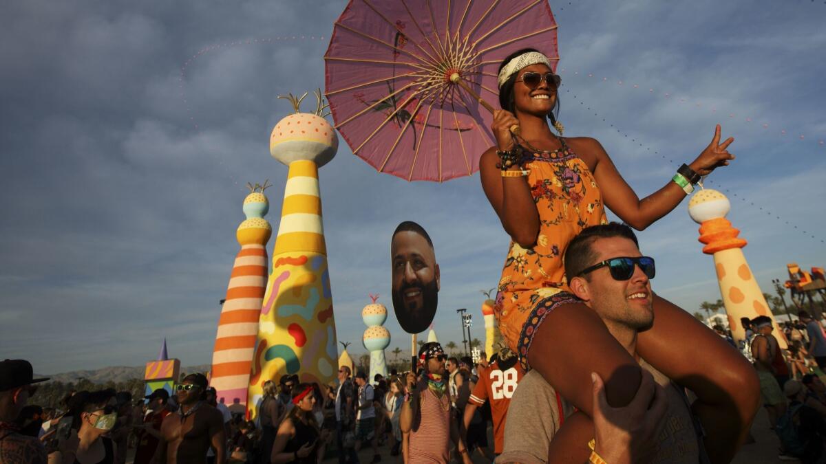Marilou Stoltenberg, 33, of Hermosa Beach, holds an umbrella while riding on the shoulders of Justin Thompson, 37, of Long Beach, during weekend one of the Coachella Valley Music and Arts Festival at the Empire Polo Grounds Sunday, April 16, 2017, in Indio, Calif.