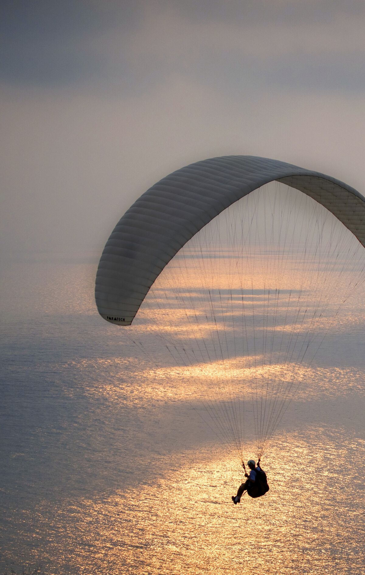 A paraglider takes flight at sunset over the ocean at Torrey Pines Gliderport in La Jolla.