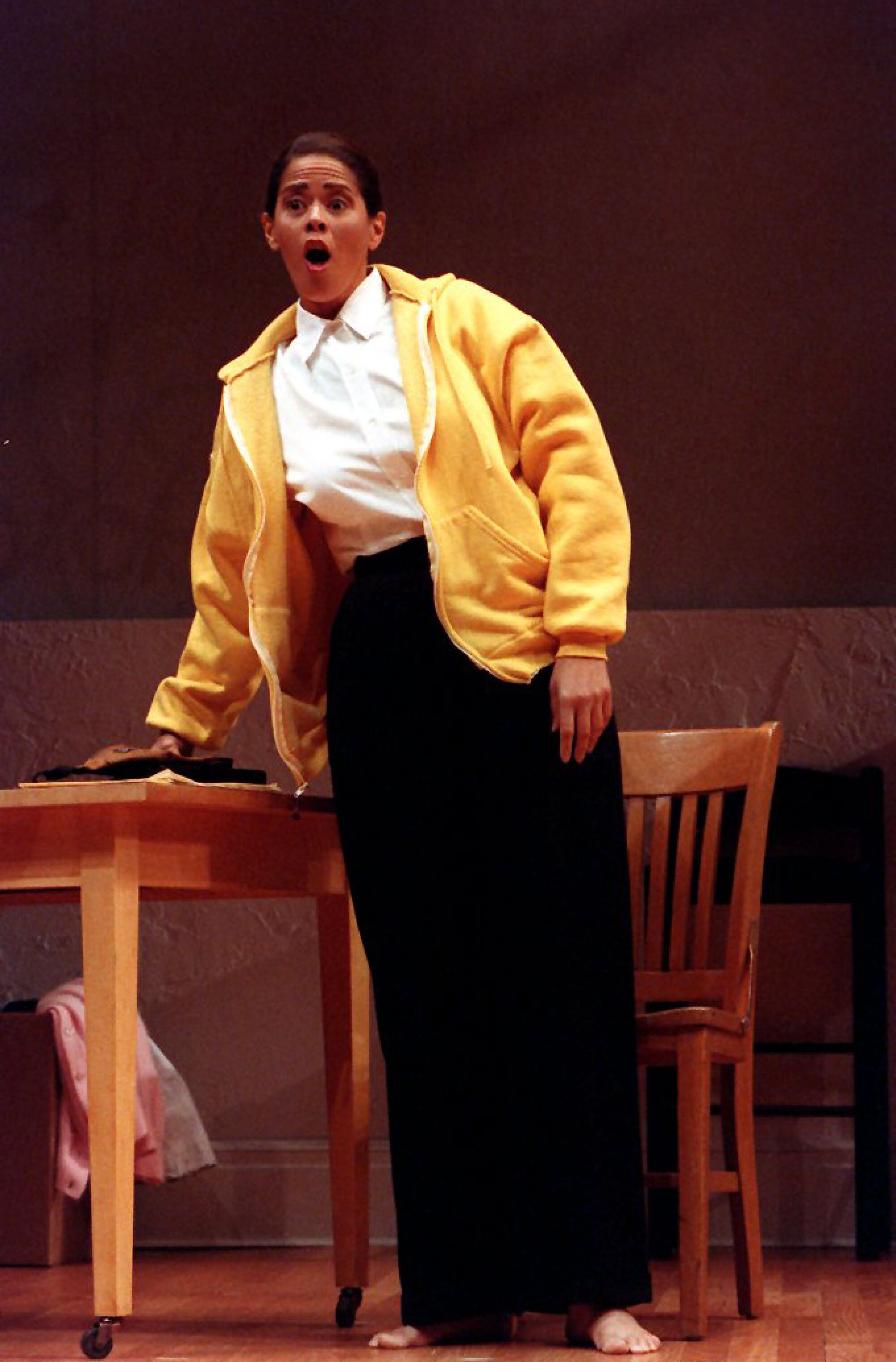 Anna Deavere Smith leans against a desk in a performance of "Twilight: Los Angeles, 1992"