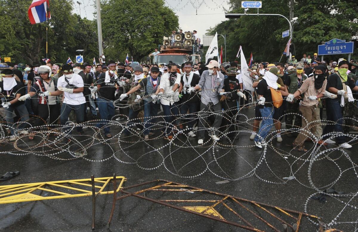 Anti-government protesters try to remove barbed wire set up by riot police during a rally in Bangkok, Thailand.