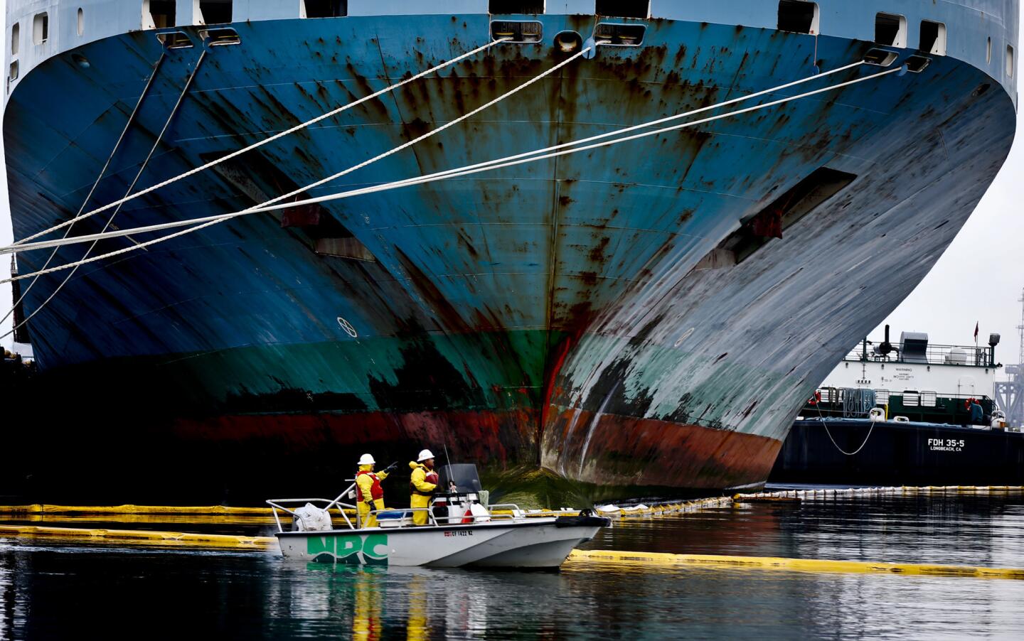 Clean-up crews using absorbent booms try to contain an oil spill leaked from a cargo ship at the Port of Los Angeles.