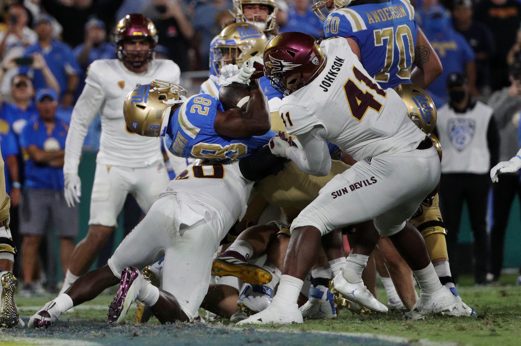 UCLA running back Brittain Brown bursts through the Arizona State defense in front of lineman Tyler Johnson.