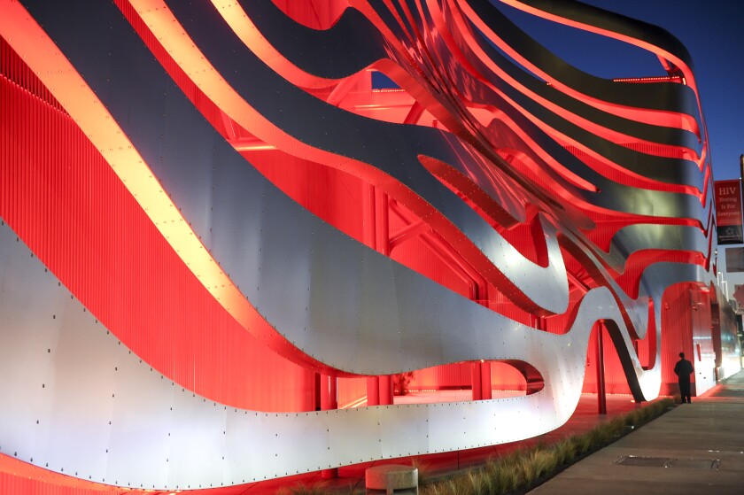 The exterior of the Petersen Automotive Museum lighted at night.