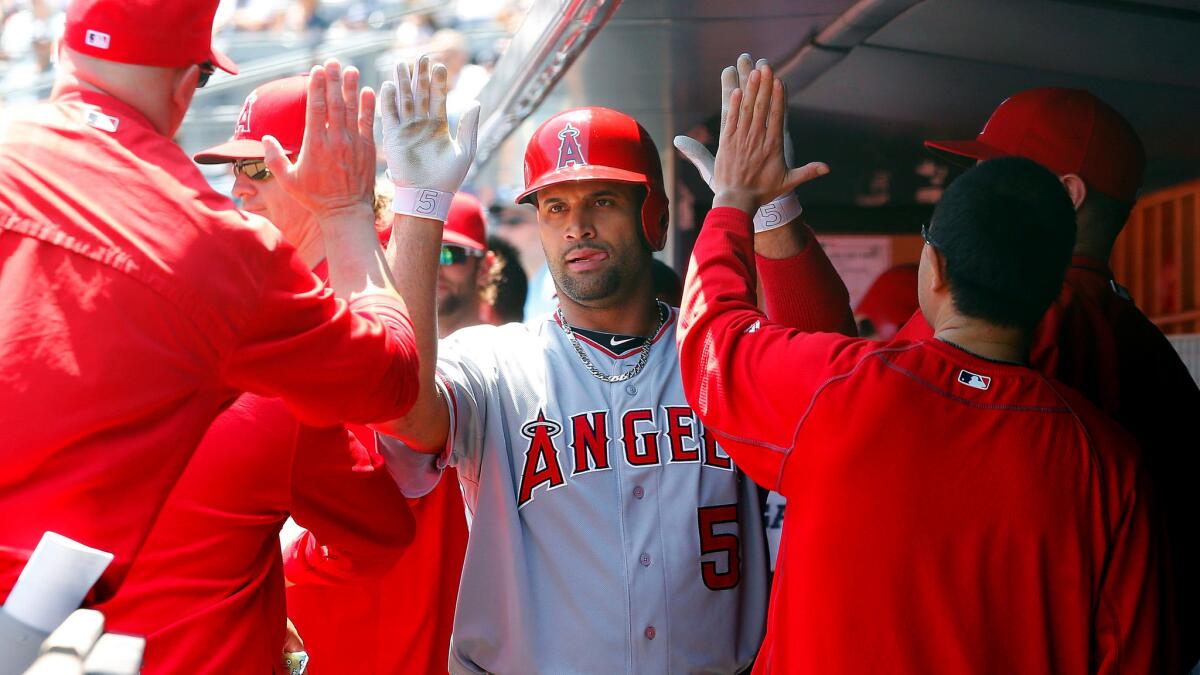 Angels designated hitter Albert Pujols is congratulated after hitting a solo home run against the Yankees in the first inning Sunday afternoon in New York.