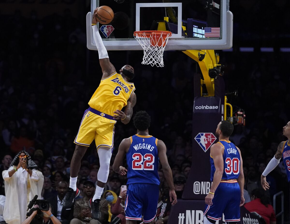 Lakers forward LeBron James dunks while opponents watch nearby