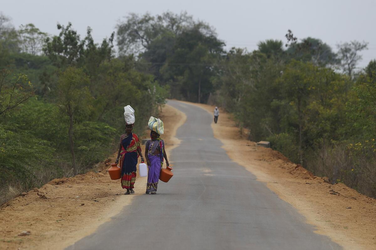 Aldeanos indios caminan hacia su aldea en las afueras de Hyderabad, India.