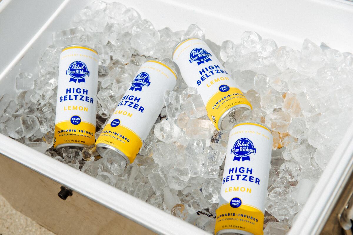 Four cans bearing the Pabst Blue Ribbon logo sitting in a cooler full of ice.