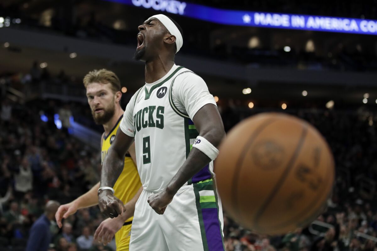 Milwaukee Bucks' Bobby Portis (9) reacts in front of Indiana Pacers' Domantas Sabonis after dunking during the second half of an NBA basketball game Wednesday, Dec. 15, 2021, in Milwaukee. (AP Photo/Aaron Gash)