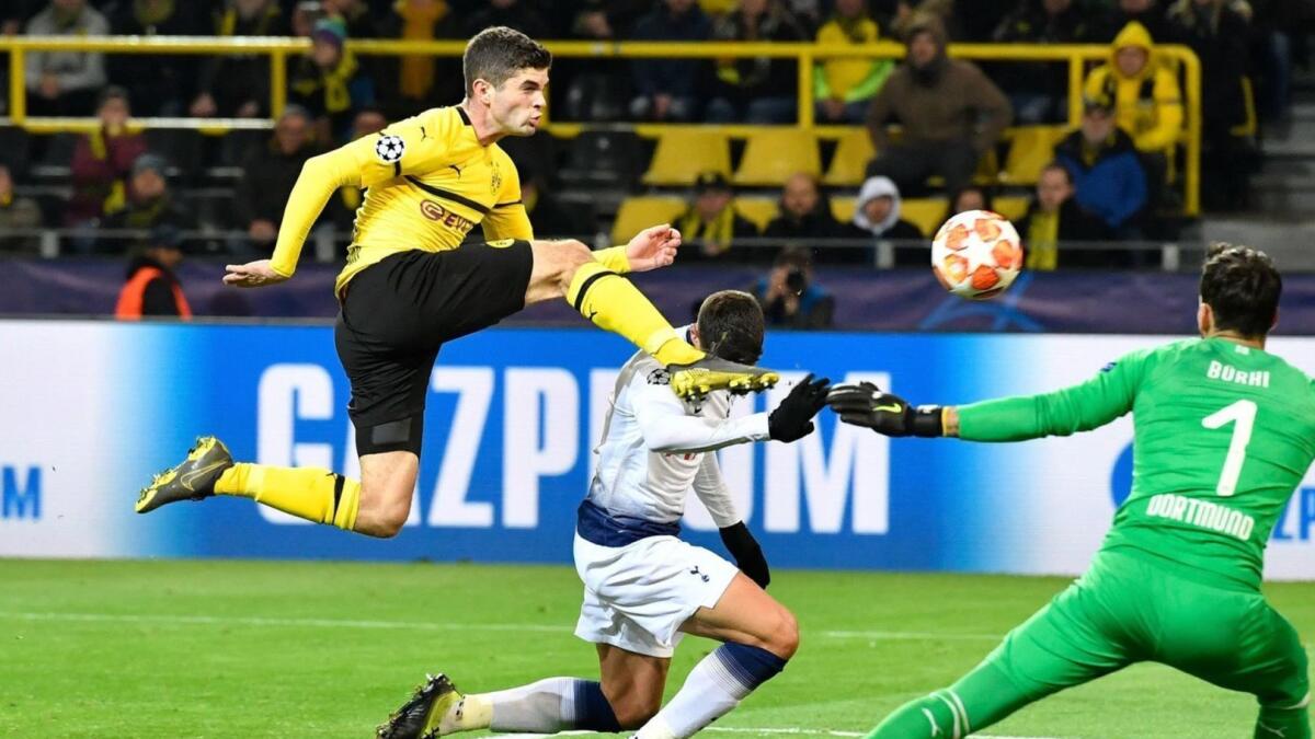 Dortmund's Christian Pulisic, left, clears the ball from Tottenham Hotspur's Erik Lamela, who was trying to score past Dortmund goalkeeper Roman Buerki on March 5.