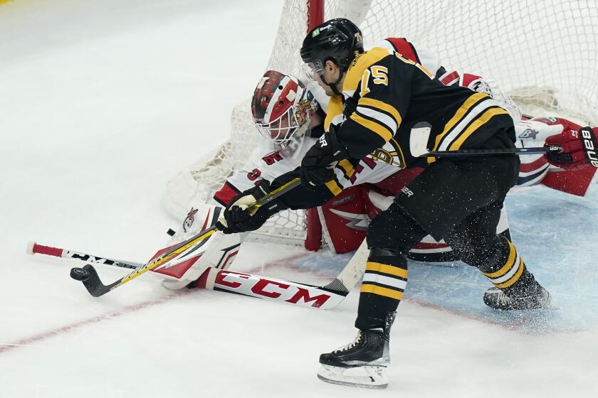 Carolina Hurricanes' Antti Raanta, of Finland, behind left, and Boston Bruins' Connor Clifton, right, vie for control of the puck in the second period of Game 4 of an NHL hockey Stanley Cup first-round playoff series, Sunday, May 8, 2022, in Boston. (AP Photo/Steven Senne)