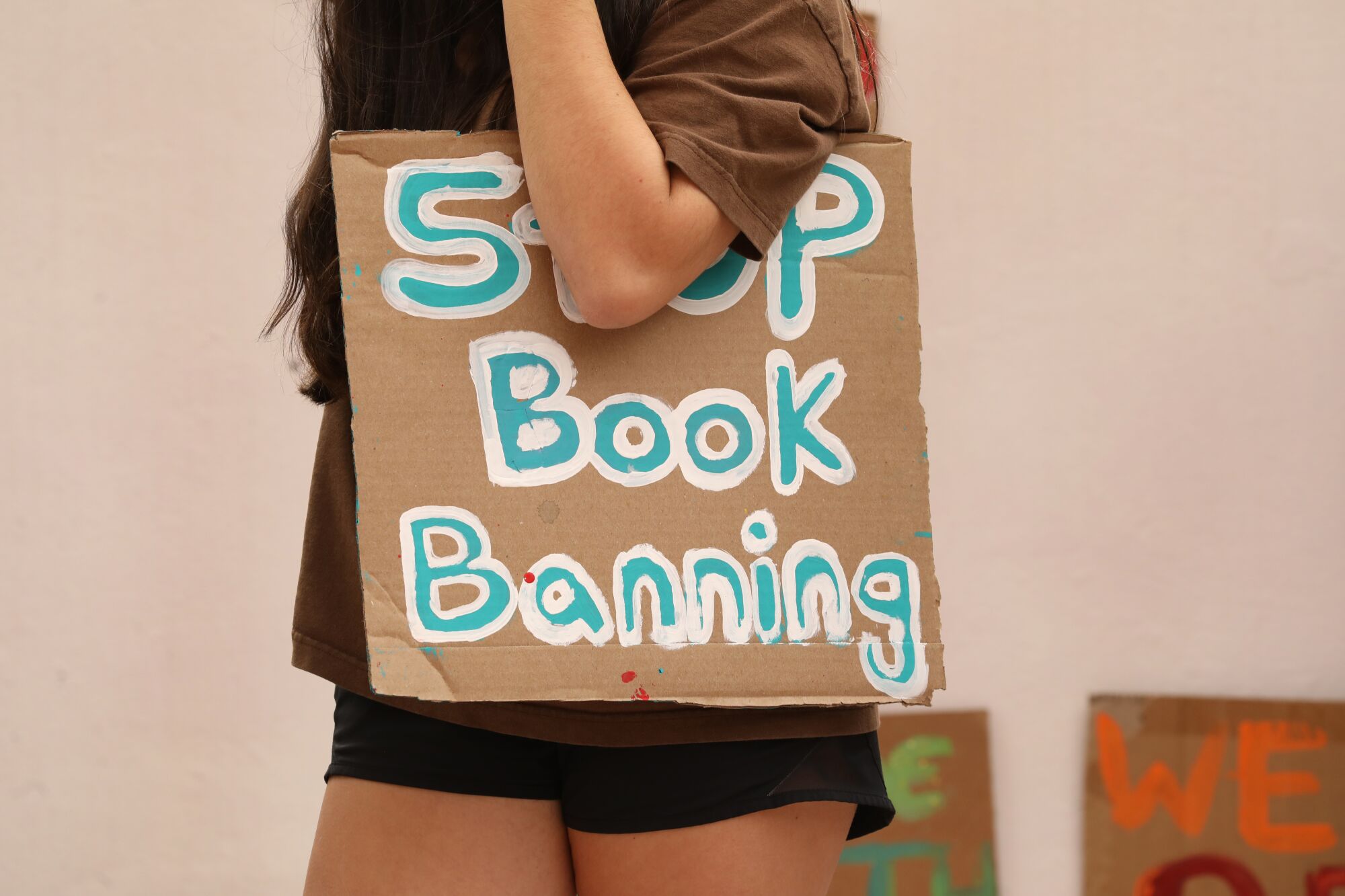 A student holds a sign that reads "Stop Book Banning" at a rally at the Orange County school board. 
