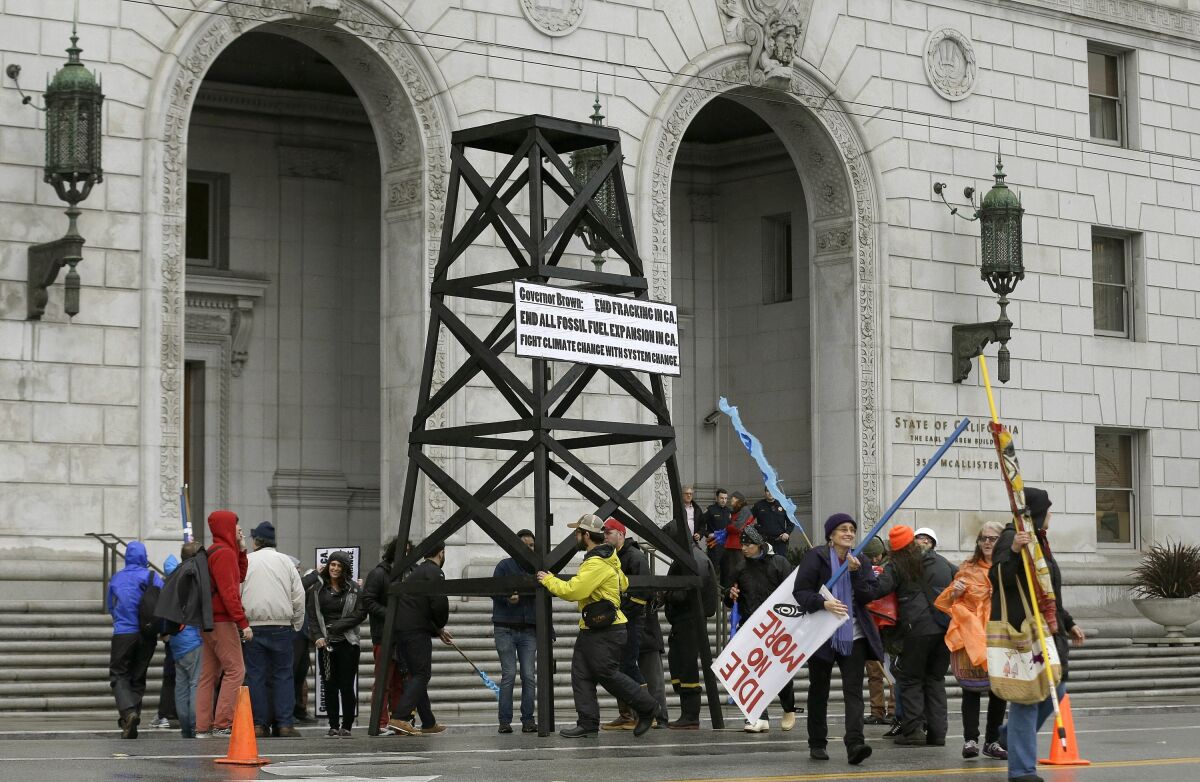 FILE - Protesters prepare to take down a makeshift oil derrick that was set up in front of the California State Office Building to protest fracking in San Francisco on Feb. 6, 2015. Leasing for new oil and gas drilling on federal land in central California is temporarily blocked under a settlement announced Monday, Aug. 1, 2022, between the state and the U.S. Bureau of Land Management. (AP Photo/Jeff Chiu, File)