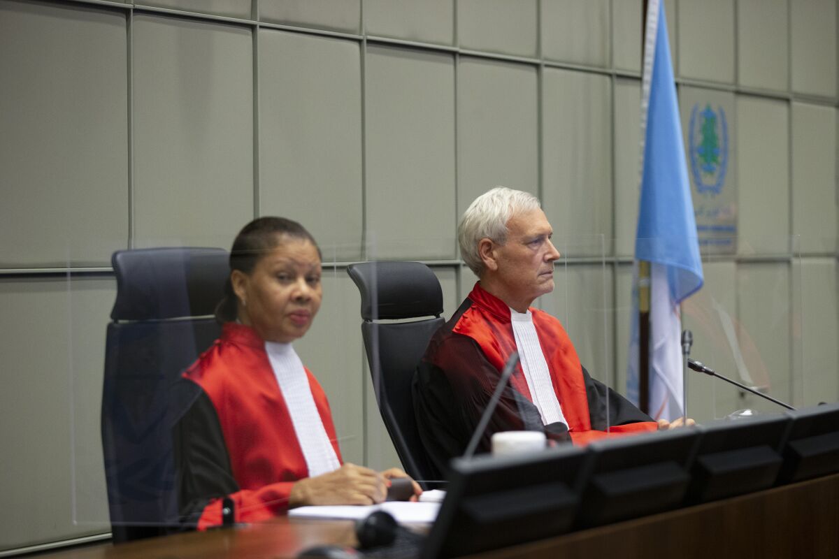 Presiding judge David Re, right, and judge Janet Nosworthy, left, pose for pictures prior to a session of the United Nations-backed Lebanon Tribunal where it is scheduled to hand down it's sentencing on Salim Jamil Ayyash, a member of the Hezbollah militant group who was convicted of involvement in the assassination of former Lebanese Prime Minister Rafik Hariri and 21 others 15 years ago, in Leidschendam, Netherlands, Friday Dec. 11, 2020. Ayyash is not in custody and is unlikely to serve any sentence. (AP Photo/Peter Dejong, Pool)