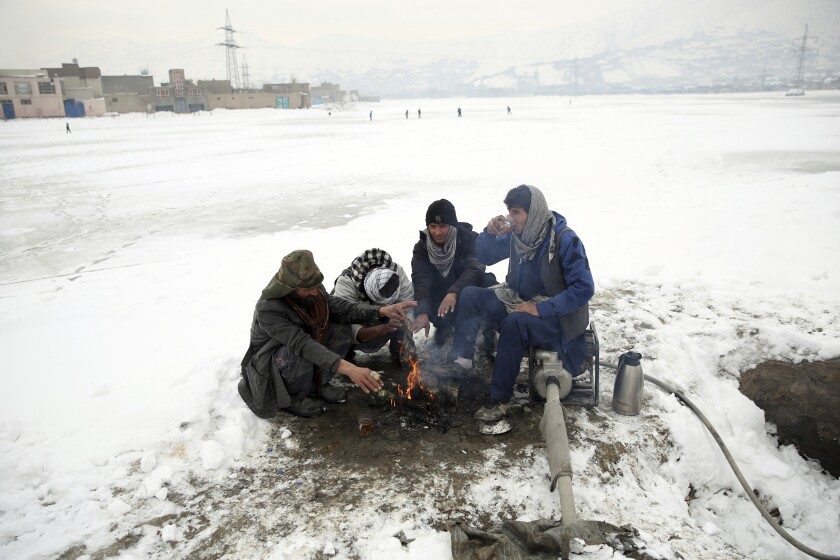 People sit around a fire to warm themselves after a heavy snowfall in Kabul, Afghanistan, Tuesday, Jan. 14, 2020. Severe winter weather has struck parts of Afghanistan and Pakistan, with heavy snowfall, rains and flash floods that left dozens dead, officials said Monday as authorities struggled to clear and reopen highways and evacuate people to safer places. (AP Photo/Rahmat Gul)