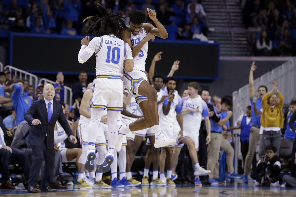 UCLA guard Chris Smith (5) celebrates with teammate Tyger Campbell after scoring during the second half of the Bruins' victory over Washington on Feb. 15, 2020, at Pauley Pavilion.