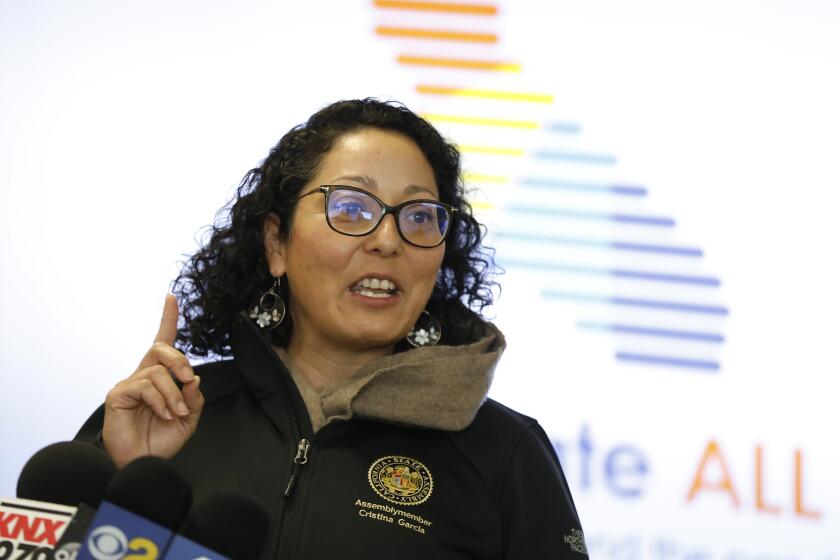 SOUTH GATE, CA - MARCH 10: California Assemblymember Cristina Garcia talks as California Governor Gavin Newsom listens during a media availability at a vaccination site at South Gate Park, South Gate in Los Angeles County the day after his State of the State Address highlighting California's continued progress in battling the pandemic and commitment to vaccine equity. Governor Newsom toured a vaccination site where local organizations are helping to vaccinate hard-to-reach communities. South Gate Park on Wednesday, March 10, 2021 in South Gate, CA. (Al Seib / Los Angeles Times).