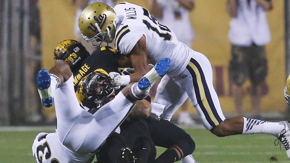UCLA teammates Anthony Jefferson, left, and Priest Willis, right, tackle Arizona State running back D.J. Foster during the Bruins' victory last month.