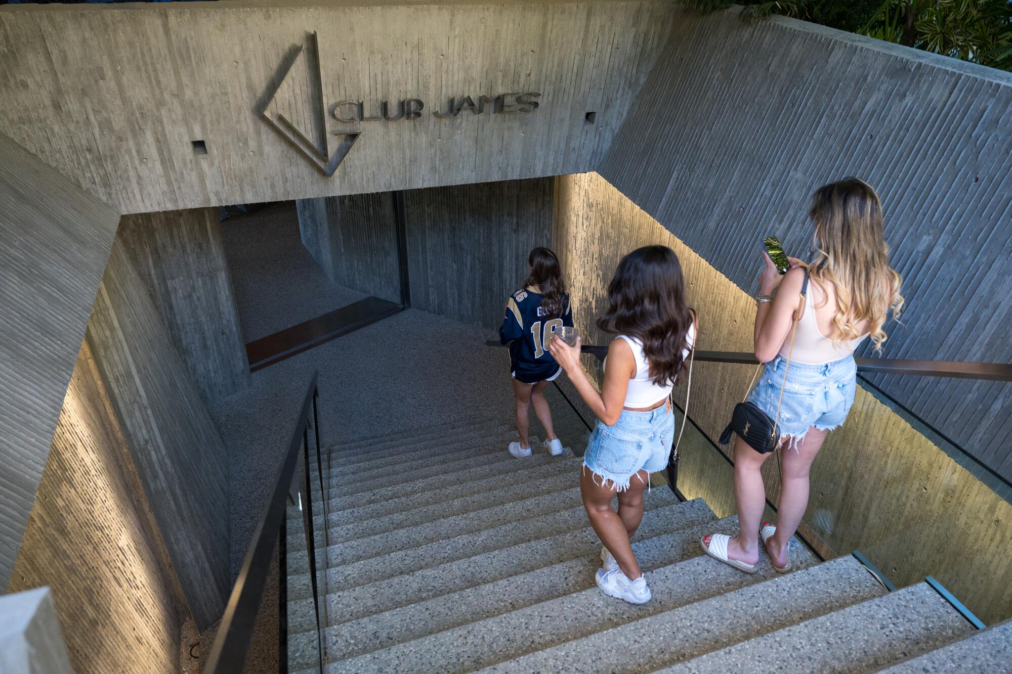 Women in shorts head down some stairs.