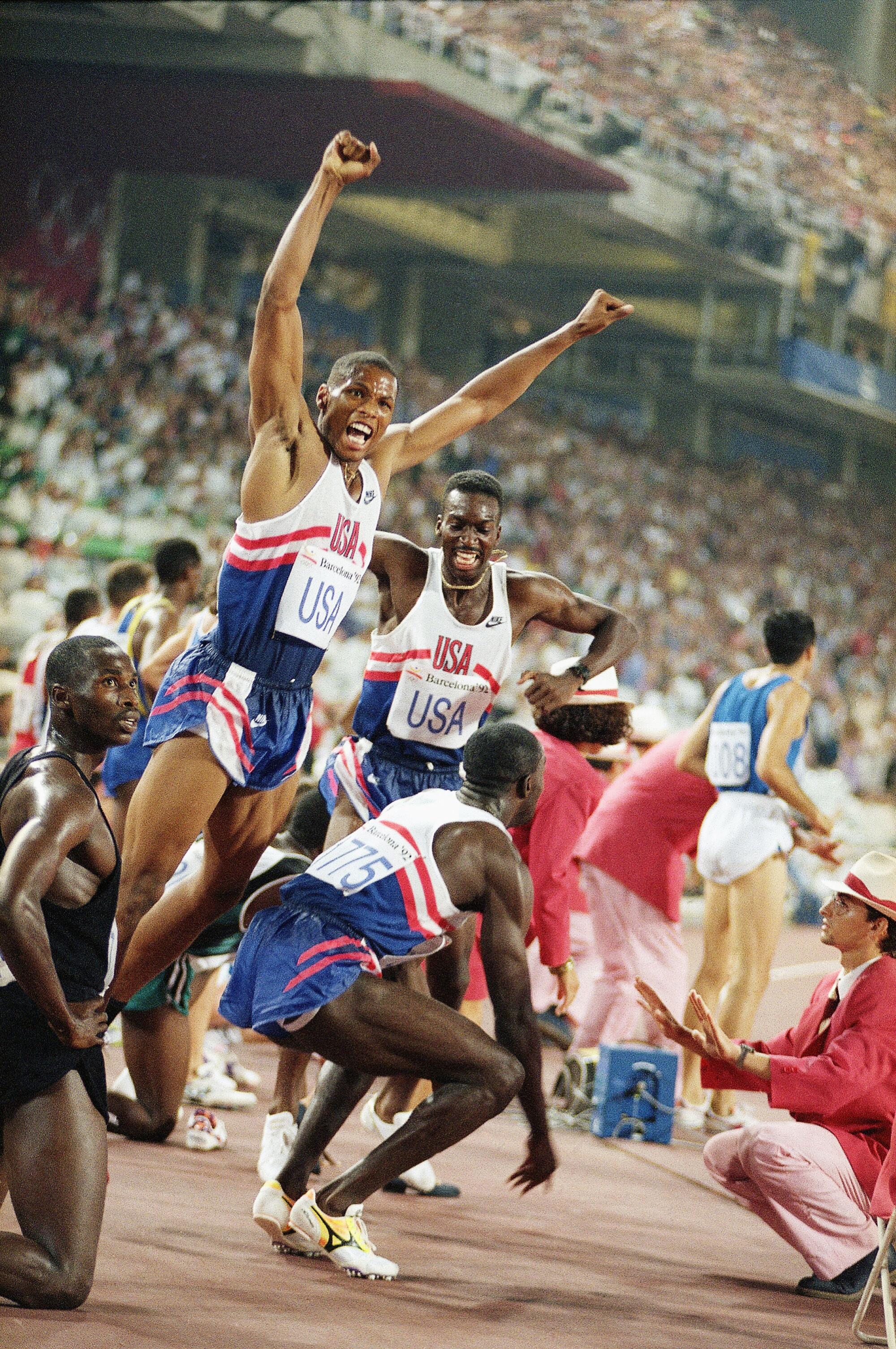 Quincy Watts leaps in celebration as teammate Steve Lewis finishes the 4x100-meter relay to secure gold.