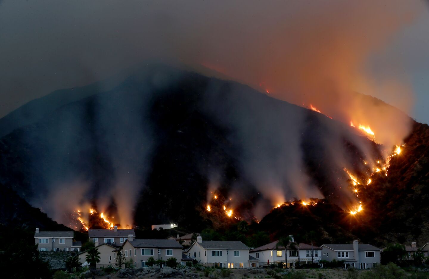 The Ranch fire burns in the hills above a cluster of homes along the San Gabriel River.