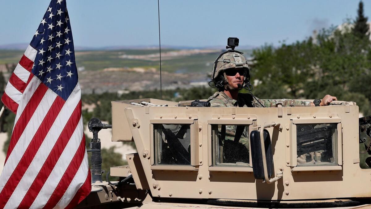 A U.S. soldier sits on his armored vehicle on a road leading to the tense front line with Turkish-backed fighters in Manbij, northern Syria, on April 4.