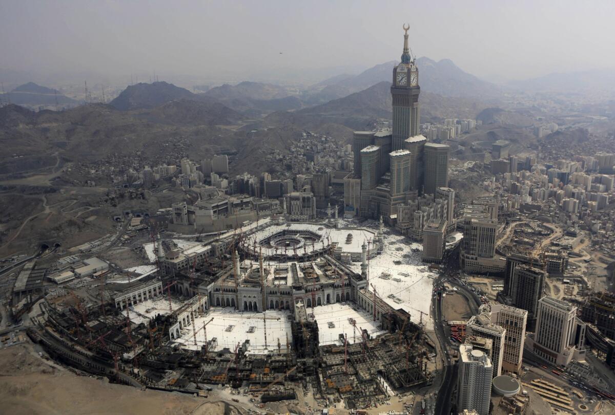 In this Sunday, Oct. 5, 2014, file photo, the Abraj Al-Bait Towers with its four-faced clocks stand over the holy Kabaa, as Muslims encircle it inside the Grand Mosque during the annual pilgrimage, known as the hajj, in the Muslim holy city of Mecca, Saudi Arabia.