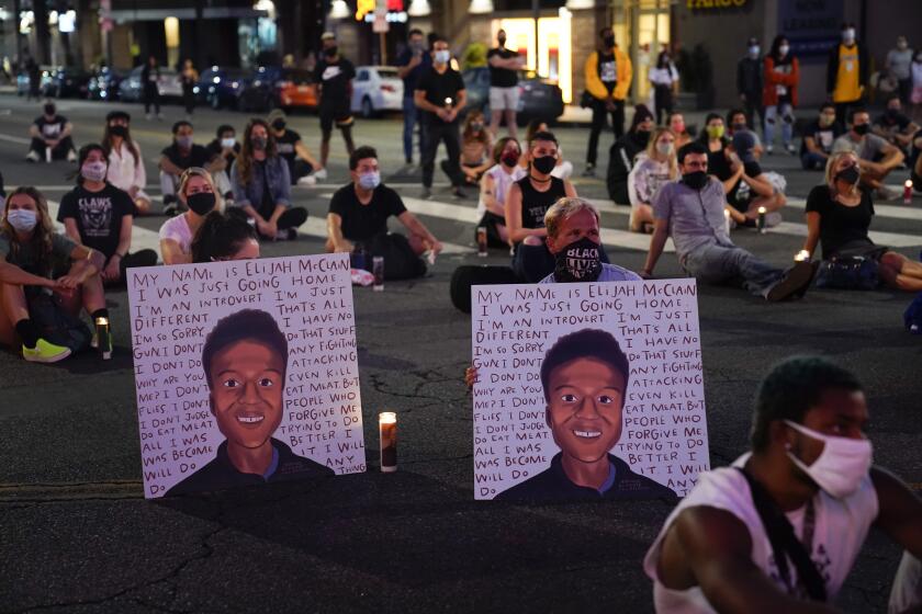 FILE - In this Aug. 24, 2020, file photo, two people hold posters showing images depicting Elijah McClain during a candlelight vigil for McClain outside the Laugh Factory in Los Angeles. An investigation into the arrest of McClain in suburban Denver criticizes how police handled the entire incident, faulting officers for their quick, aggressive treatment of the 23-year-old unarmed Black man and department overall for having a weak accountability system. (AP Photo/Jae C. Hong, File)