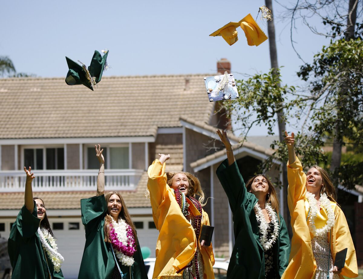A group of Edison High School graduates toss their caps into the air in Huntington Beach.