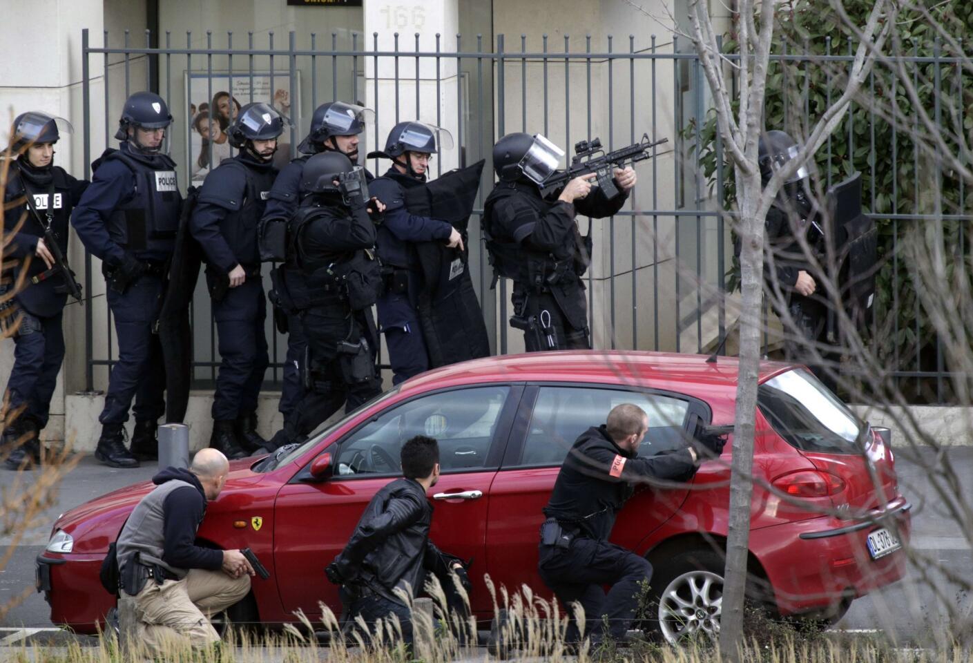 French Research and Intervention Brigades (BRI) officers gather near the post office where an armed man is holed up with two hostages in Colombes, outside Paris.