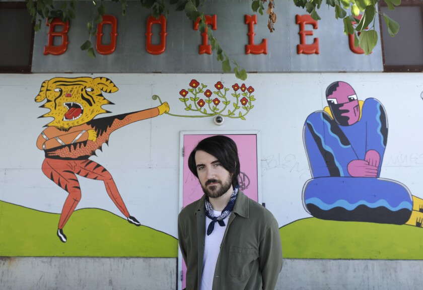 Talent booker Kyle Wilkerson stands in front of a cartoony mural at the Bootleg Theater