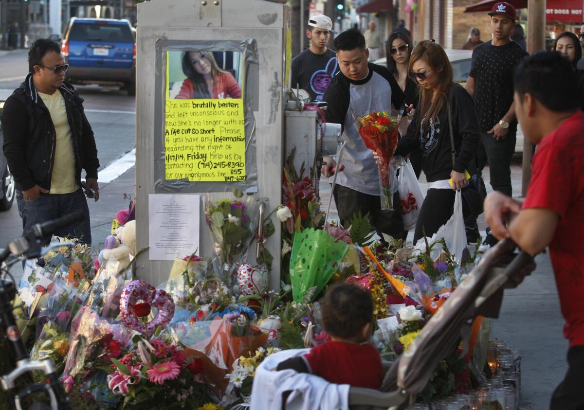 A woman, right, brings flowers to a large memorial for her friend, Kim Pham, 23, of Huntington Beach, who was beaten to death outside The Crosby nightclub in downtown Santa Ana.